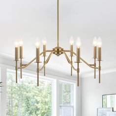 a chandelier hanging from the ceiling in a living room with white walls and windows