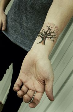 a person with a tree tattoo on their arm holding the hand of another person's wrist