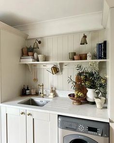 a washer and dryer sitting in a kitchen next to a counter with flowers on it