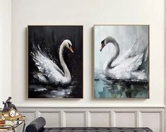 two paintings of swans are hanging on the wall