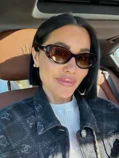 a woman wearing sunglasses sitting in the back seat of a car