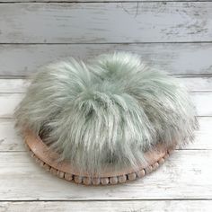 a white and green furry hat sitting on top of a wooden table next to a wall