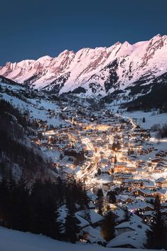 a town is lit up at night in the mountains