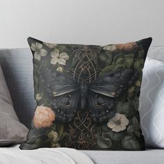 a black butterfly sitting on top of a flowery pillow throw pillow with an ornate design