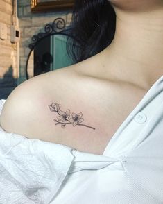 a woman's shoulder with a flower tattoo on the left side of her chest