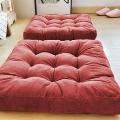 two red futons sitting on top of a wooden floor next to each other