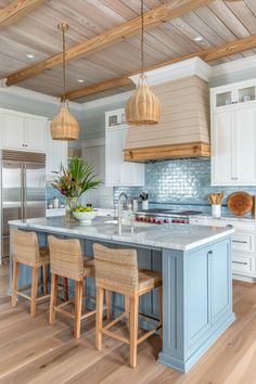 a kitchen with blue and white cabinets, wood flooring and wooden ceiling lights hanging from the rafters