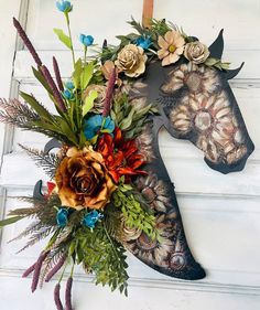 a horse head is decorated with flowers and leaves on the front door to decorate it's home