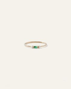 a gold ring with an emerald stone on the side and a white diamond in the middle