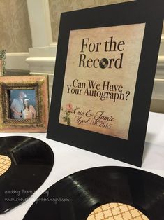 two black record records sitting on top of a table next to a framed photo and an album