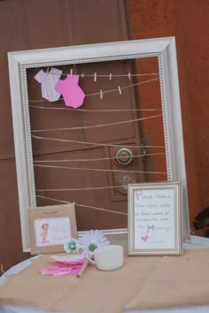 a table topped with a white frame covered in paper and clothes hanging from it's sides