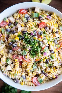 a white bowl filled with pasta salad on top of a wooden table