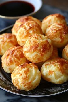 a plate full of cheese rolls next to a bowl of sauce