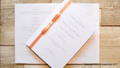 an orange ribbon on top of a white wedding card