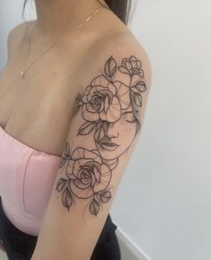 a woman's shoulder with flowers and leaves on her arm, in black ink