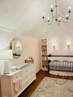 a baby's room with a crib, dresser and chandelier