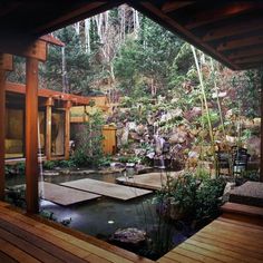 the inside of a house with a pond and wooden decking in front of it