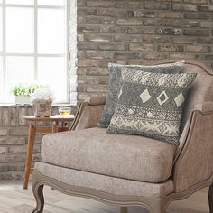 a living room with a chair, table and brick wall in the backround