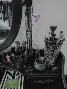 an assortment of makeup brushes and other items on a black table next to a mirror