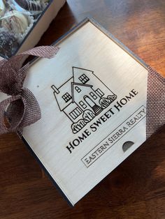 a home sweet home wooden box with ribbon on the front and side, sitting on a table