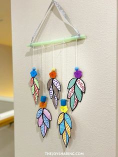 three colorful feathers hanging on a wall