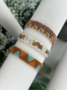 three beaded bracelets sitting on top of each other in front of some plants