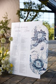 a wedding ceremony sign with flowers on the side