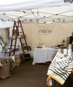 an outdoor market with tables and ladders in the background, including clothing on display