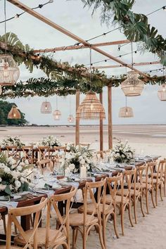 an outdoor dining area with wooden chairs and tables set up for dinner on the beach