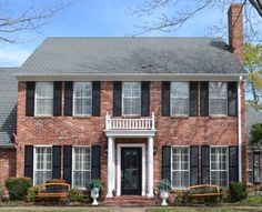 a large brick house with black shutters and white trim on the front door is shown