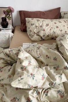 an unmade bed with floral sheets and pillows