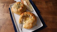 two apple pies on a white plate with a knife