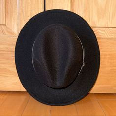 a black hat sitting on top of a wooden floor