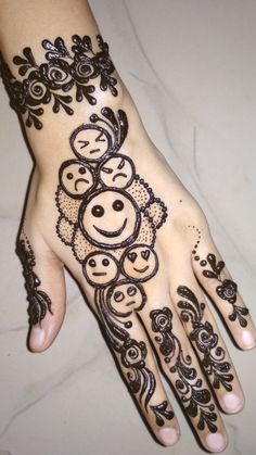 a henna design on someone's hand that is decorated with flowers and smiley faces