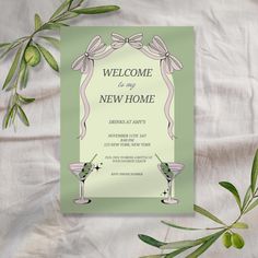 a green and white welcome card with two martini glasses on it, surrounded by greenery