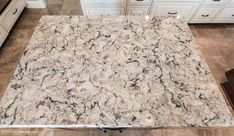 a marble counter top in a kitchen with white cabinets and brown floor tiles on the ground