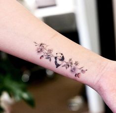 a small tattoo on the arm of a woman with pandas and wildflowers