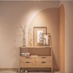 a wooden dresser sitting in front of a mirror on top of a wall next to a vase