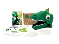 a green stuffed animal with its mouth open next to it's packaging and contents