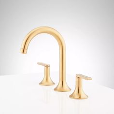 two gold faucets on a white surface