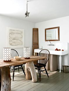 a wooden table sitting in the middle of a room next to two chairs and a sink