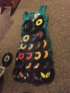 an owl made out of records sitting on the floor next to a pile of cds