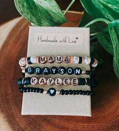 three beaded bracelets sitting on top of a wooden table next to a plant