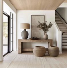 a living room with two vases and a lamp on top of a wooden table