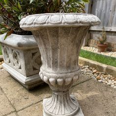 a cement planter sitting on top of a sidewalk next to a potted plant