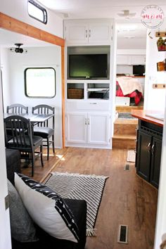 the interior of a tiny home with wood floors and white cabinets, black chairs, and an open kitchen area