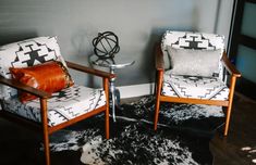 two chairs sitting next to each other on top of a hard wood floor covered in black and white cowhide