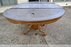 a wooden table sitting on top of a cement ground next to a house with windows