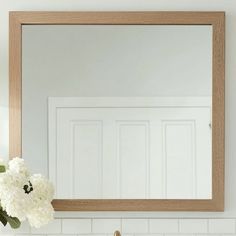 a bathroom sink with a mirror above it and flowers on the counter top next to it