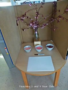 a laptop computer sitting on top of a wooden table next to a vase filled with flowers